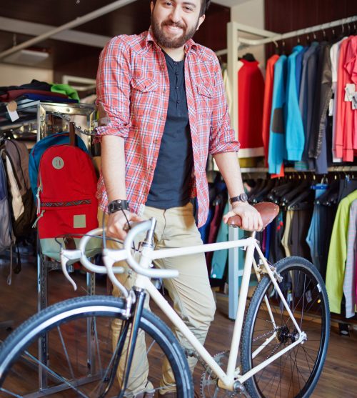 Portrait of a handsome man with bicycle looking at camera in sports shop