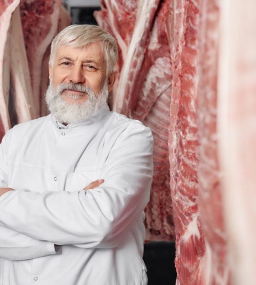 butcher-standing-near-pork-carcasses-with-crossed-hands