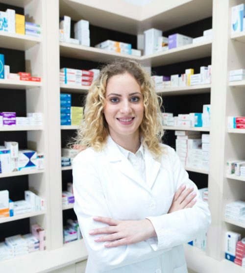 portrait-of-female-pharmacist-in-drug-store-standing-in-front-of-shelves-with-medications