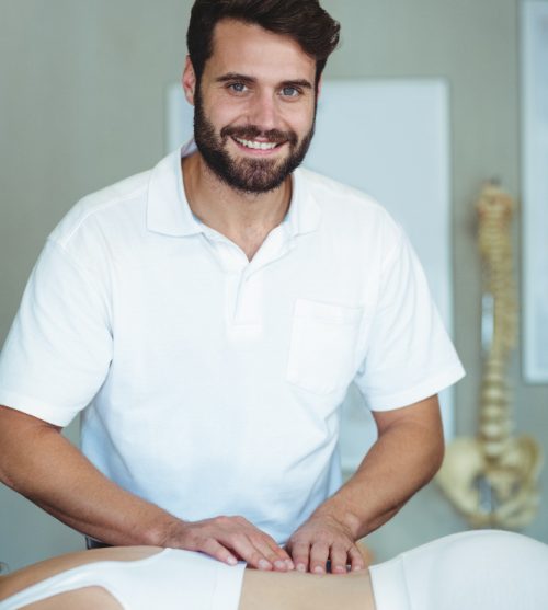 smiling-physiotherapist-giving-back-massage-to-woman